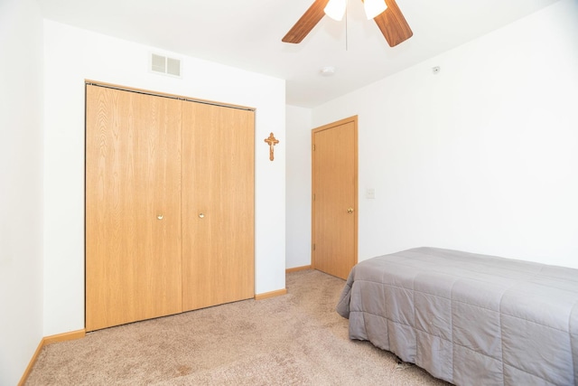 bedroom with light colored carpet, ceiling fan, and a closet