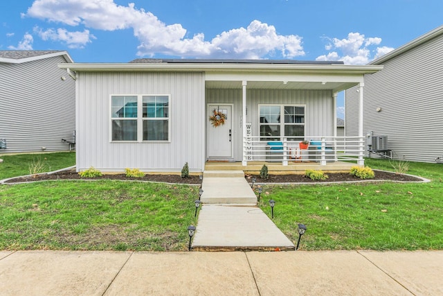 view of front facade featuring central AC, a porch, board and batten siding, and a front yard