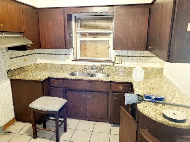 kitchen featuring light stone countertops, light tile patterned flooring, backsplash, and sink