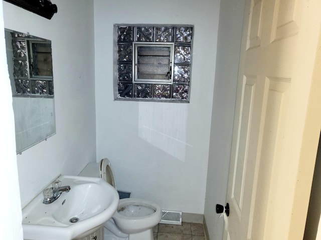 bathroom with toilet, tile patterned flooring, and sink