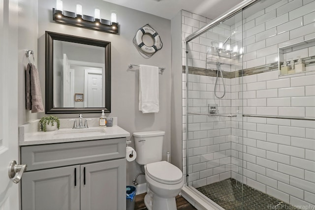 bathroom with an enclosed shower, vanity, and toilet