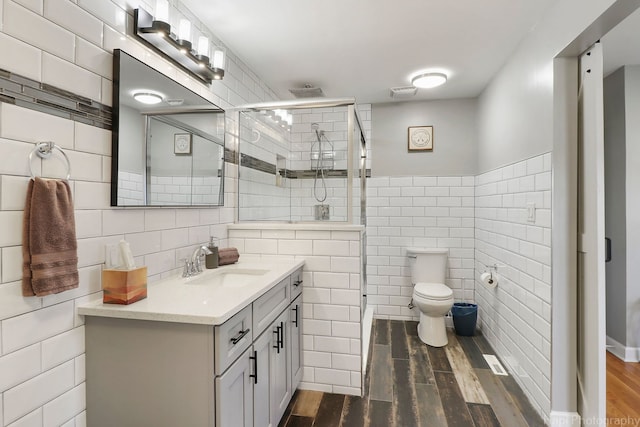 bathroom featuring tile walls, wood-type flooring, vanity, and an enclosed shower