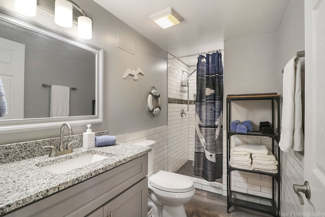 bathroom featuring toilet, a shower with shower curtain, tile walls, and vanity