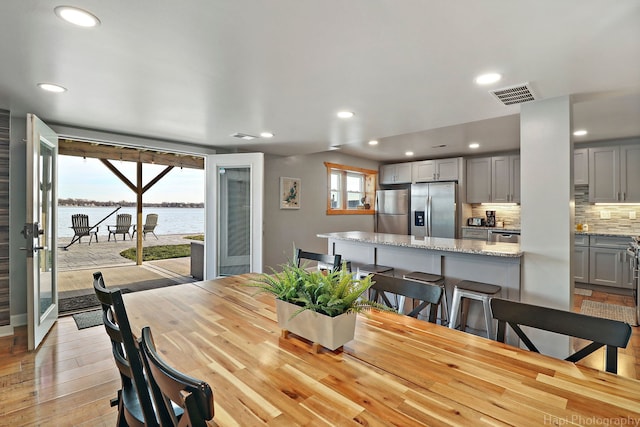 dining space with a water view and light hardwood / wood-style floors