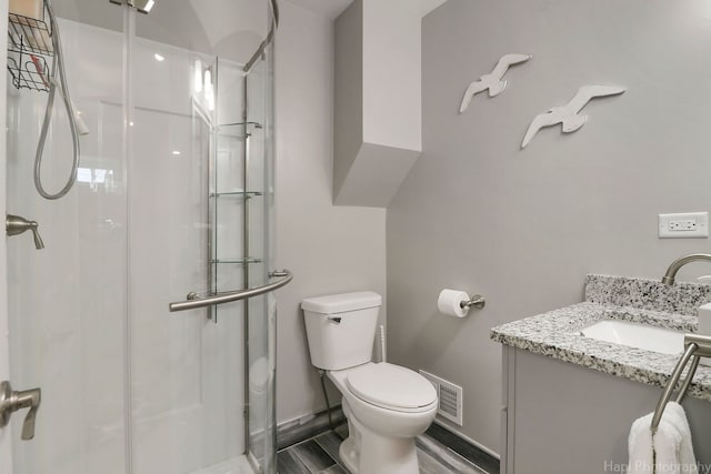 bathroom featuring toilet, a shower with shower door, and vanity