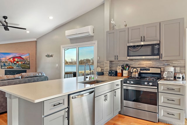 kitchen with tasteful backsplash, vaulted ceiling, an AC wall unit, sink, and appliances with stainless steel finishes