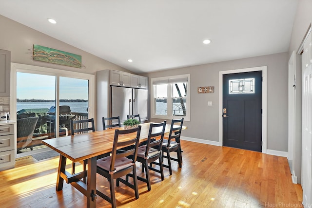 dining room featuring a water view, light hardwood / wood-style floors, and lofted ceiling