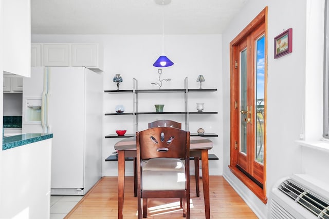 dining room featuring a wall unit AC and light hardwood / wood-style flooring