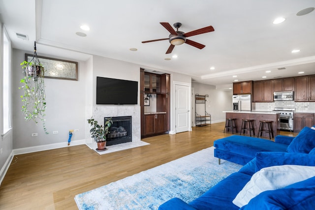 living room featuring ceiling fan, ornamental molding, and light hardwood / wood-style floors