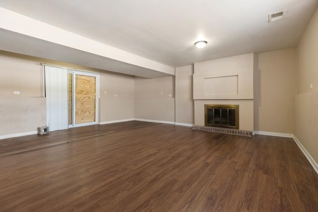 unfurnished living room with a brick fireplace and dark hardwood / wood-style floors