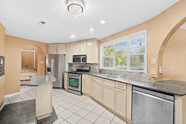 kitchen featuring stainless steel appliances, kitchen peninsula, light tile patterned floors, decorative backsplash, and sink