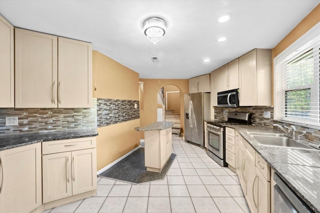 kitchen featuring sink, stainless steel appliances, cream cabinetry, and tasteful backsplash