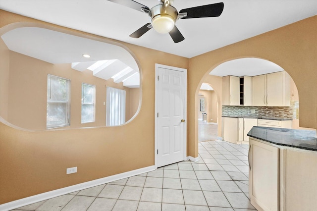 kitchen with light tile patterned floors, ceiling fan, cream cabinetry, and backsplash