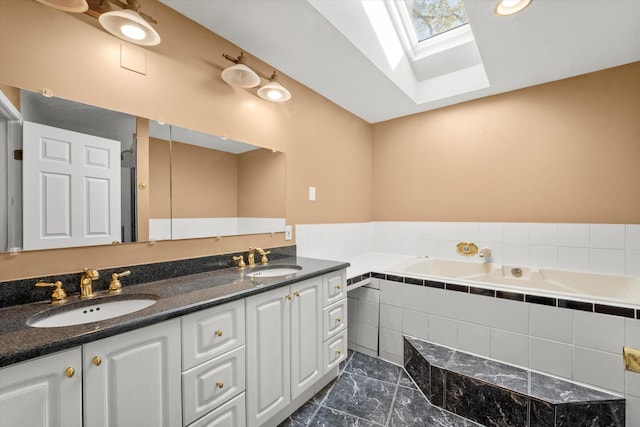 bathroom with vanity, lofted ceiling with skylight, and tiled bath