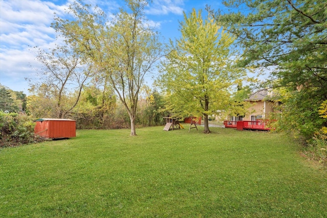 view of yard featuring a deck, a playground, and a shed