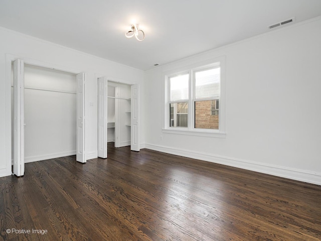 unfurnished bedroom featuring two closets and dark hardwood / wood-style flooring