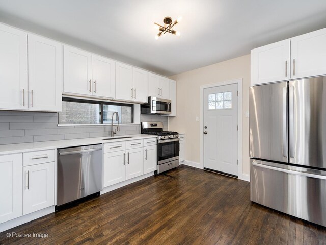 kitchen featuring stainless steel appliances, sink, white cabinetry, backsplash, and dark hardwood / wood-style flooring