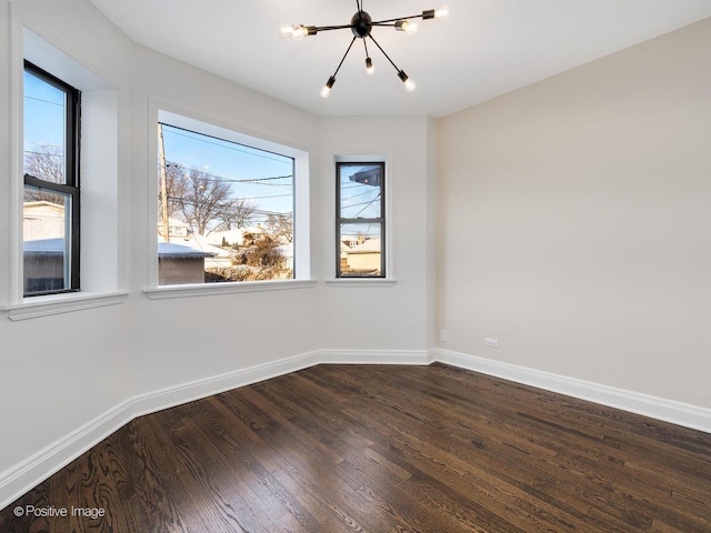 spare room featuring dark hardwood / wood-style flooring and a chandelier