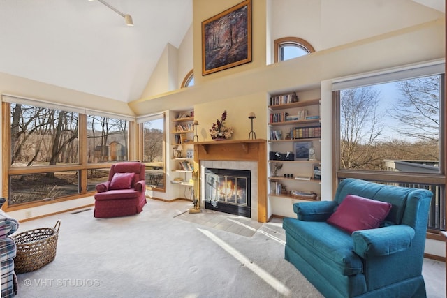 living room featuring light colored carpet, a healthy amount of sunlight, high vaulted ceiling, and a tile fireplace