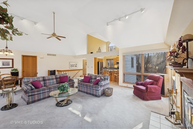 carpeted living room featuring a tiled fireplace, track lighting, high vaulted ceiling, and ceiling fan