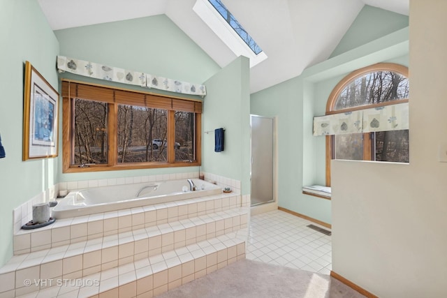 bathroom with tile patterned floors, vaulted ceiling with skylight, and shower with separate bathtub