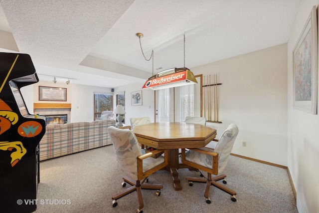 carpeted dining space with a tiled fireplace and a textured ceiling