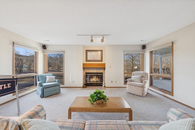 living room with light colored carpet, a tile fireplace, and rail lighting