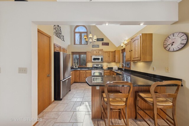 kitchen with sink, a breakfast bar, stainless steel appliances, vaulted ceiling, and kitchen peninsula