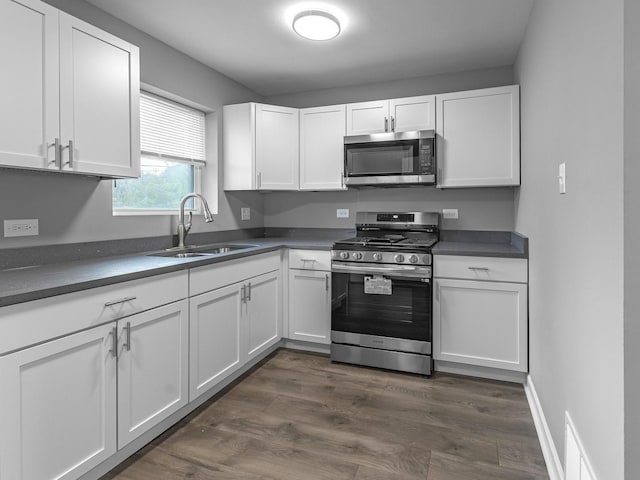 kitchen with sink, dark wood-type flooring, appliances with stainless steel finishes, and white cabinetry