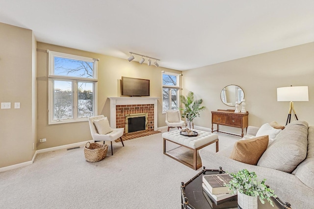 living room featuring a brick fireplace, track lighting, and carpet