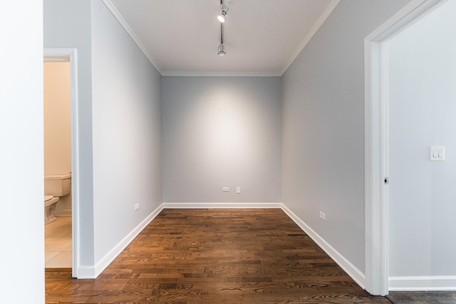 empty room with dark wood-type flooring, rail lighting, and crown molding