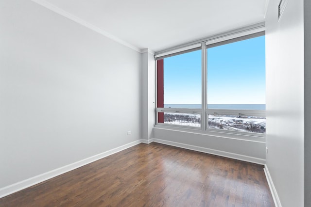 unfurnished room featuring dark hardwood / wood-style floors, ornamental molding, and a water view