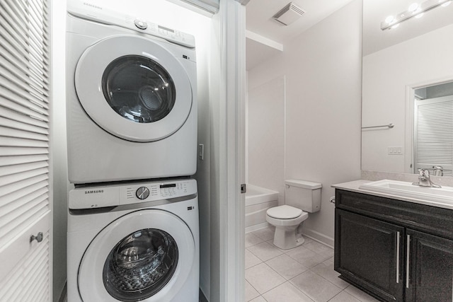 laundry area featuring sink, stacked washing maching and dryer, and light tile patterned floors