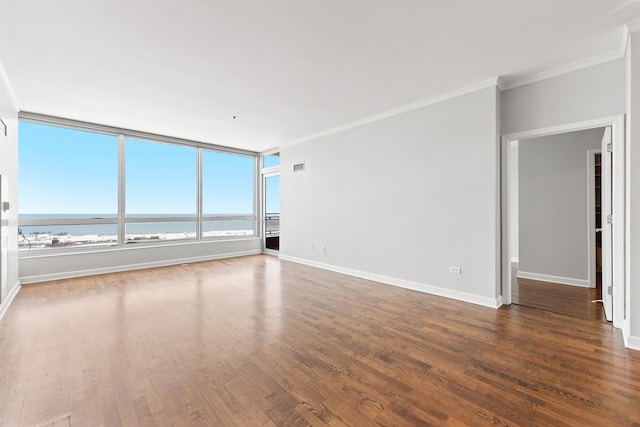 empty room featuring dark wood-type flooring, crown molding, and a water view