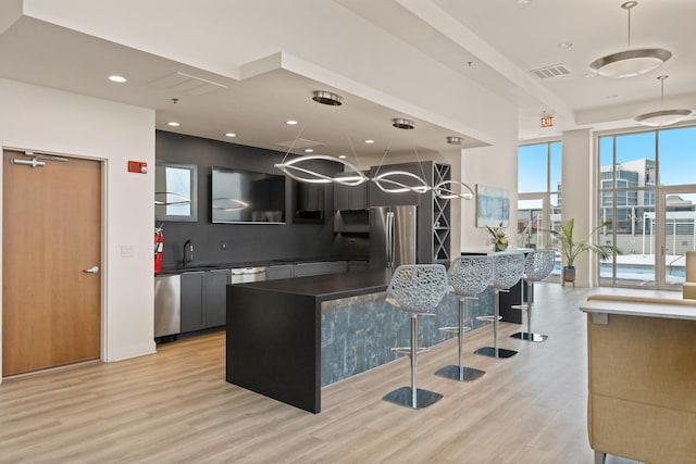 kitchen featuring sink, appliances with stainless steel finishes, light hardwood / wood-style floors, and hanging light fixtures