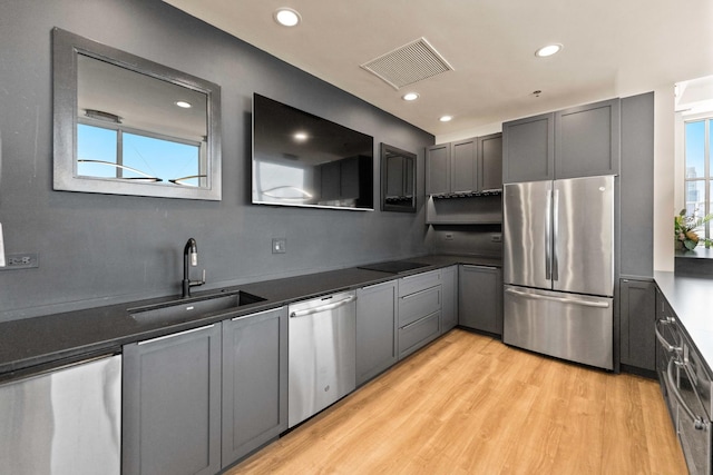 kitchen featuring stainless steel appliances, light hardwood / wood-style floors, a wealth of natural light, and sink