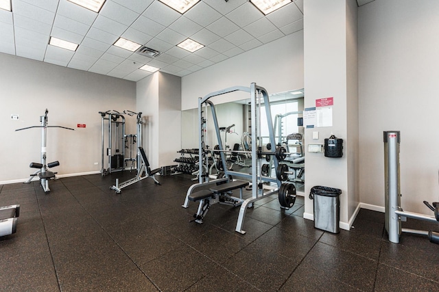 exercise room featuring a towering ceiling and a drop ceiling