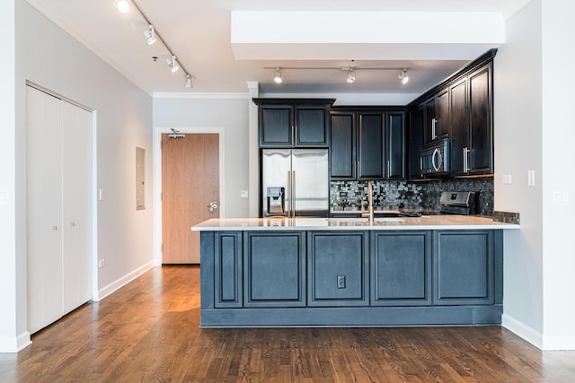 kitchen featuring sink, tasteful backsplash, kitchen peninsula, dark hardwood / wood-style floors, and appliances with stainless steel finishes