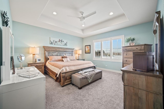 bedroom with ceiling fan, light carpet, and a raised ceiling