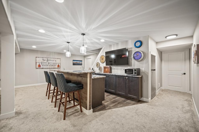 bar featuring light stone countertops, dark brown cabinetry, carpet flooring, and hanging light fixtures