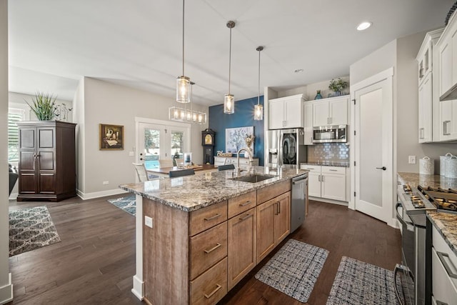 kitchen featuring sink, stainless steel appliances, a center island with sink, and white cabinetry