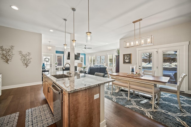 kitchen with sink, a center island with sink, ceiling fan, and hanging light fixtures