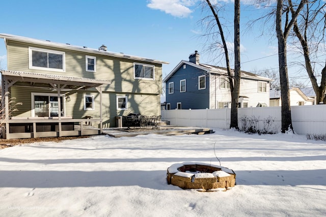 snow covered back of property with a fire pit