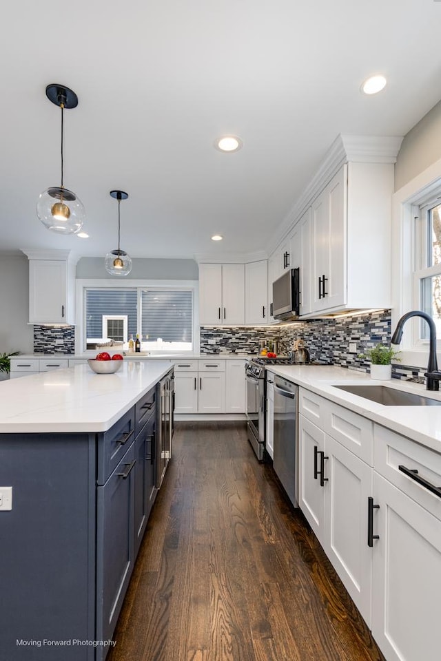 kitchen with stainless steel dishwasher, white cabinetry, pendant lighting, and sink