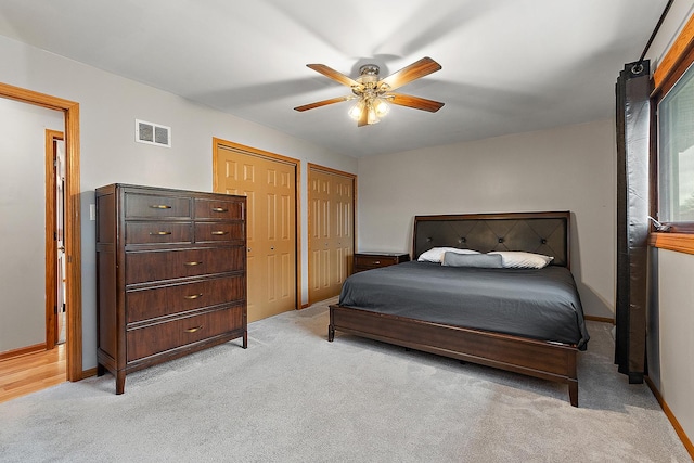 carpeted bedroom with two closets and ceiling fan