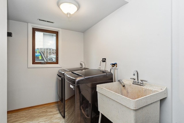 laundry room with sink, separate washer and dryer, and wood-type flooring