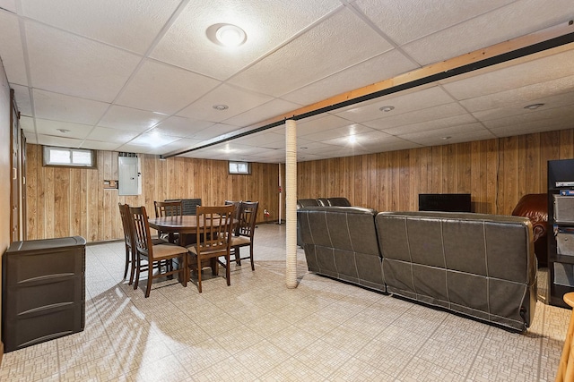 dining room with wooden walls, a drop ceiling, and electric panel