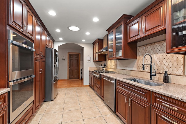 kitchen featuring light stone countertops, appliances with stainless steel finishes, backsplash, and sink