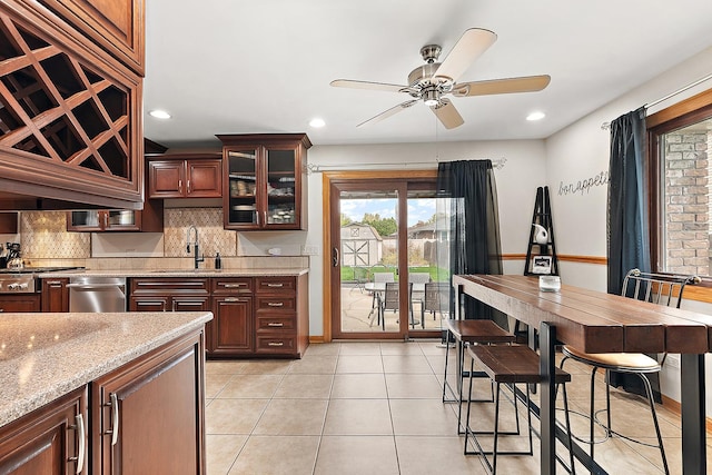 kitchen with sink, light tile patterned flooring, ceiling fan, tasteful backsplash, and light stone countertops