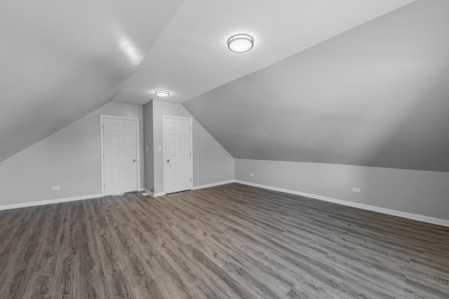 additional living space featuring dark wood-type flooring and vaulted ceiling